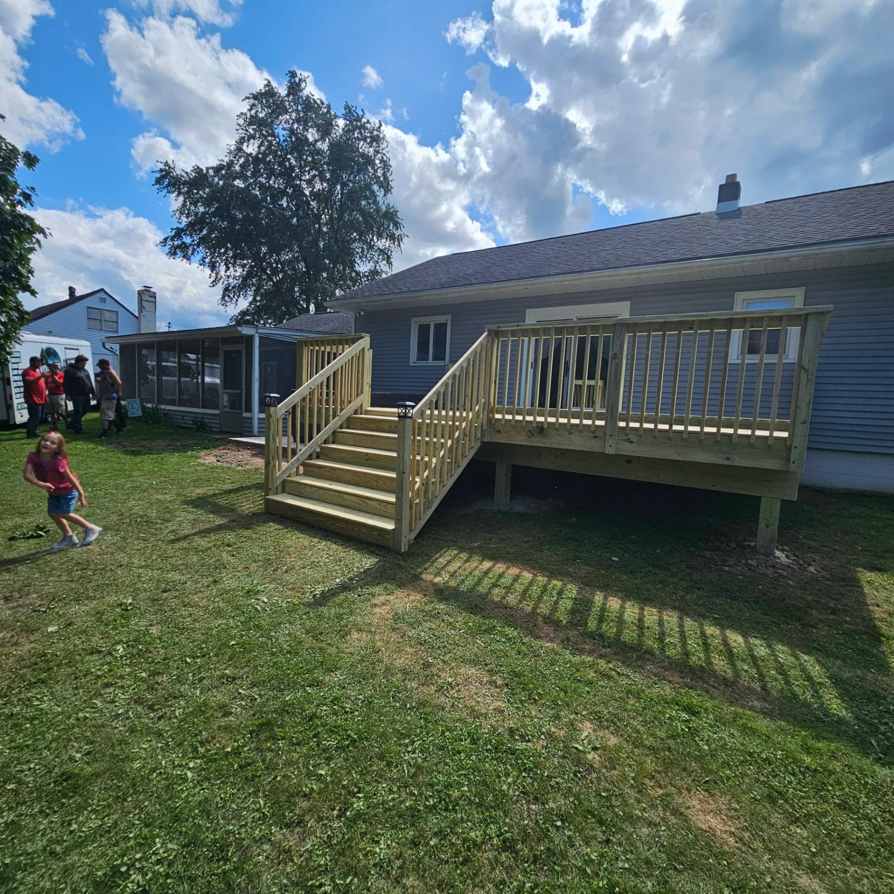 Finished elevated backyard deck with center stairs on a dark gray ranch home