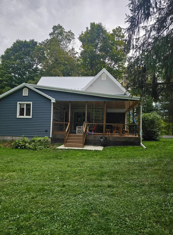 Blue farmhouse with new back porch addition, metal roof and stone veneer wall
