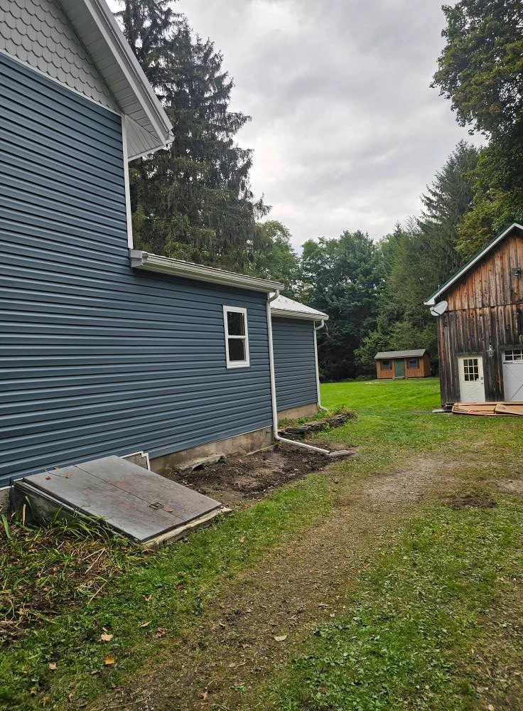 Side elevation of a country home with new blue vinyl siding, white trim and seamless gutters