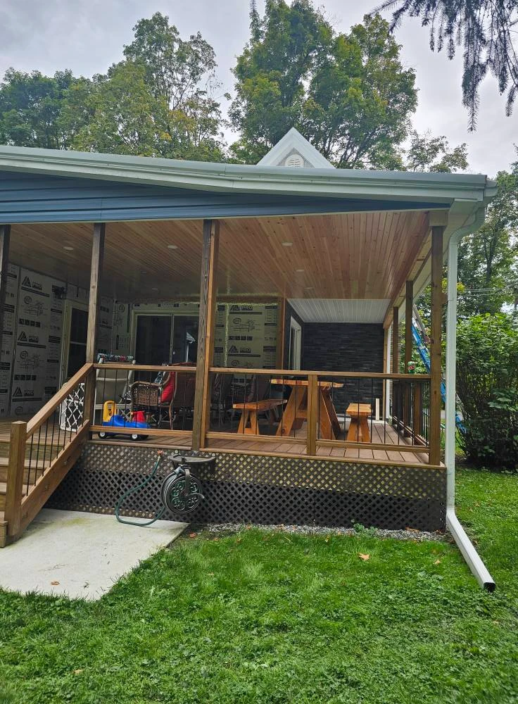 Covered back deck with pine ceiling, stone veneer accent wall and picnic table