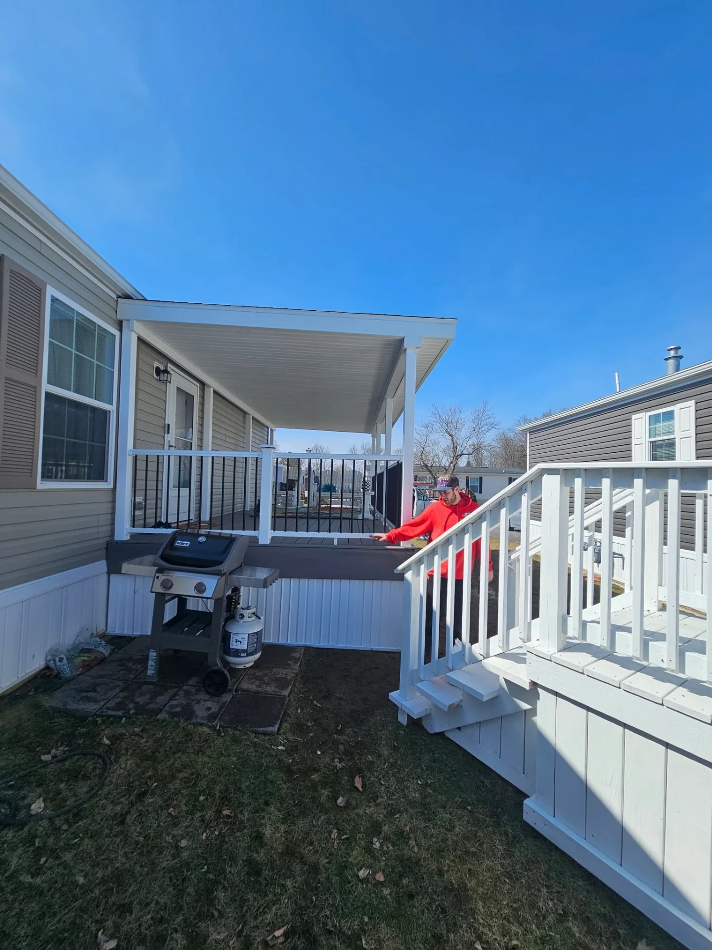 Finished covered deck with white posts, aluminum spindle railings and grill area