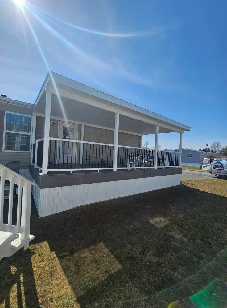 Wide shot of a finished covered deck with white posts, gray decking and aluminum spindle railings