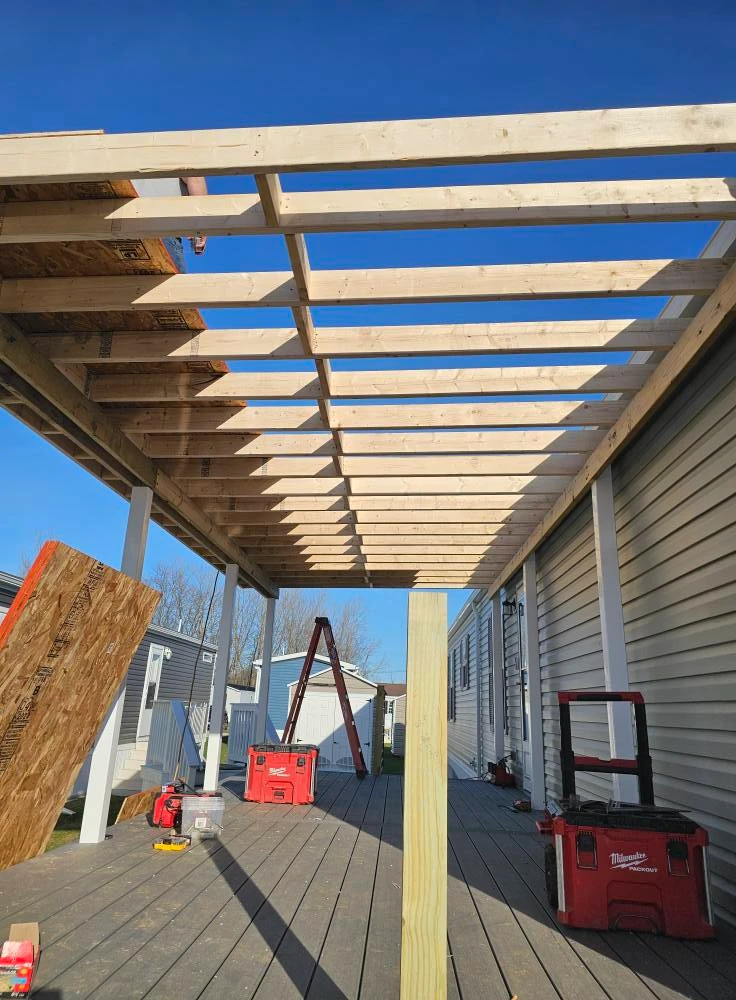 Pressure treated roof framing going up over a new composite deck