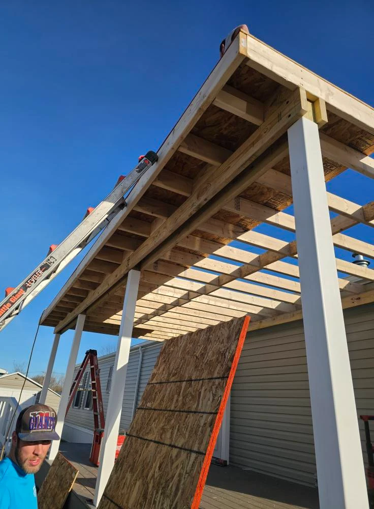 Underside view of fresh pressure treated roof framing over a new covered deck