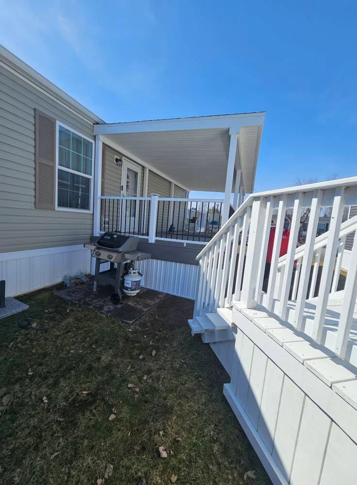 Side view of a finished covered deck with aluminum railings and a grill area below