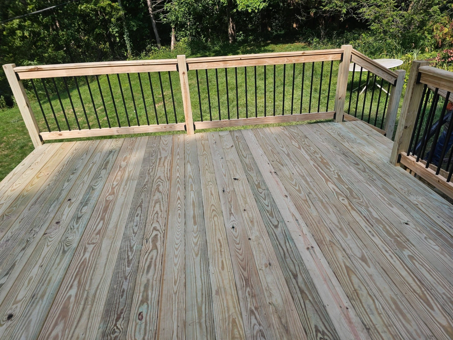 Pressure treated deck with black aluminum spindle railings overlooking a green backyard