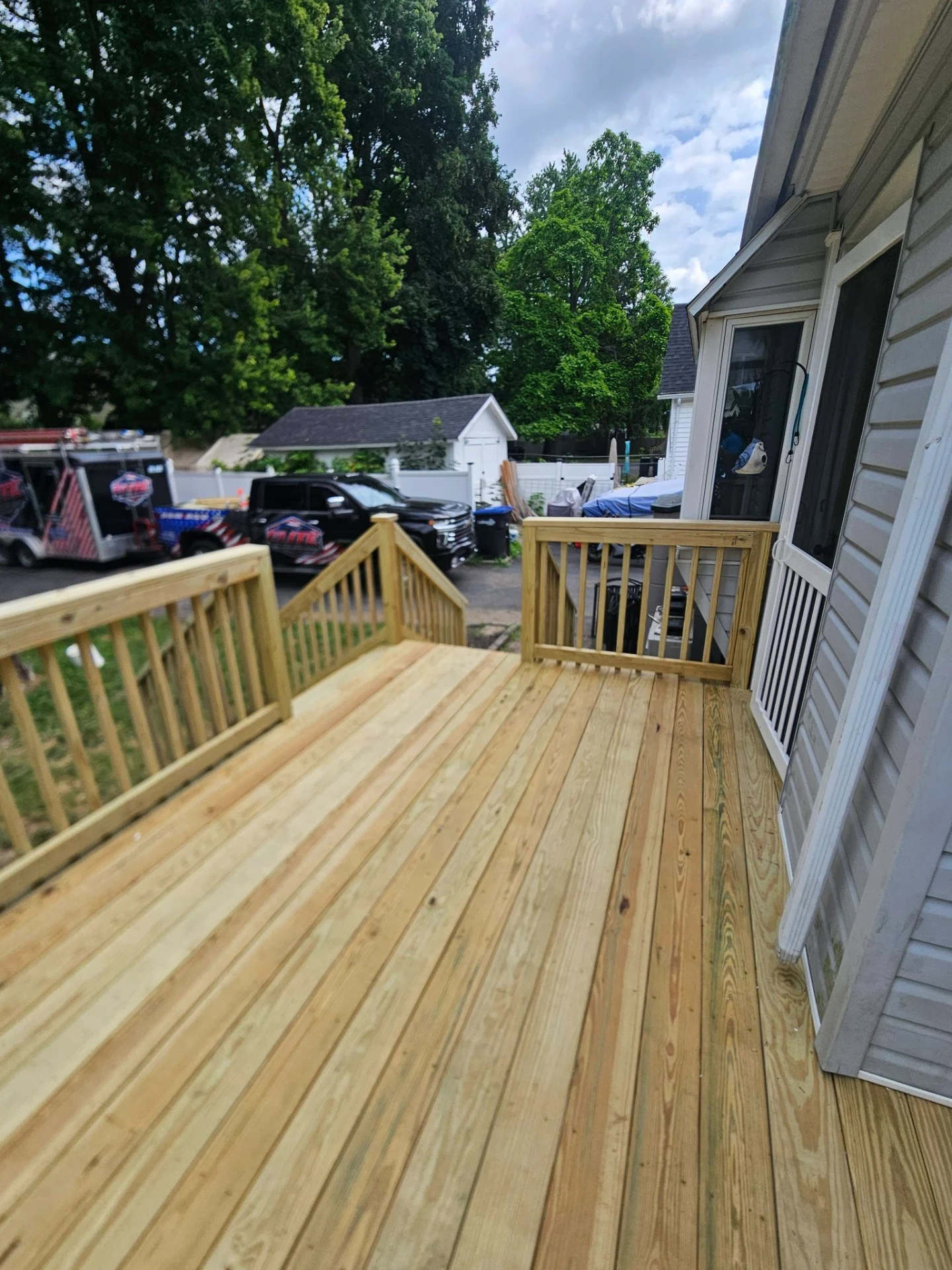 Finished pressure treated backyard deck with matching wood railings and stairs to the yard