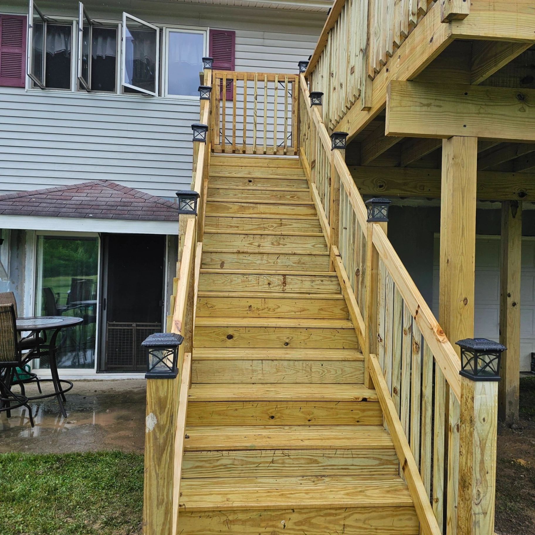 Front view looking up a wide elevated deck staircase with black solar post cap lights