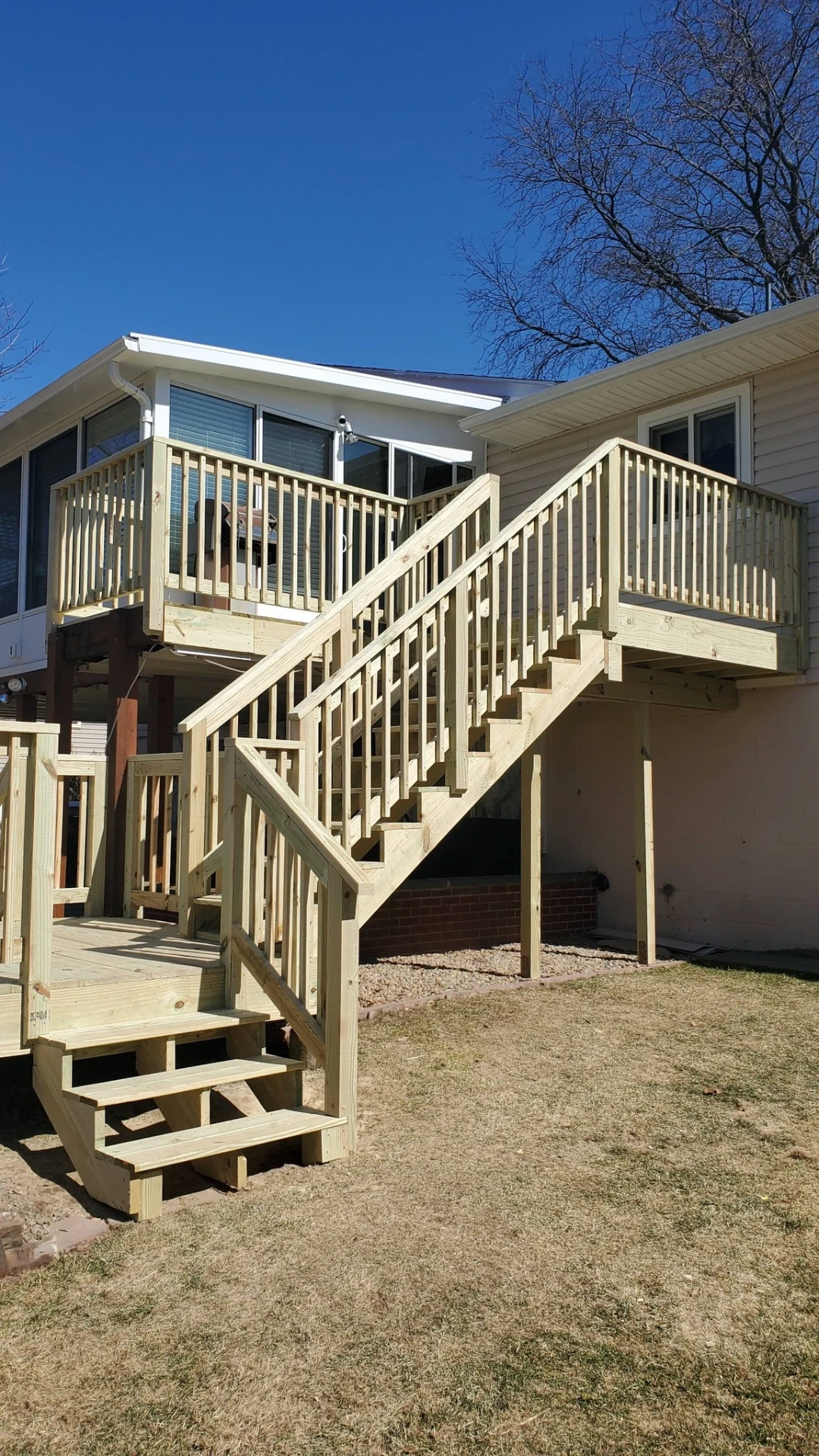 Elevated deck with switchback pressure treated stairs and intermediate landing on a tan ranch home