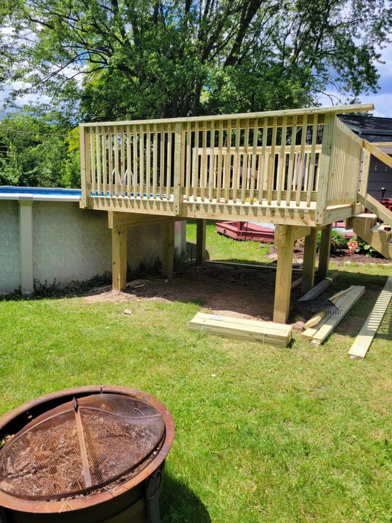 Elevated pressure treated deck with railings built next to an above ground pool