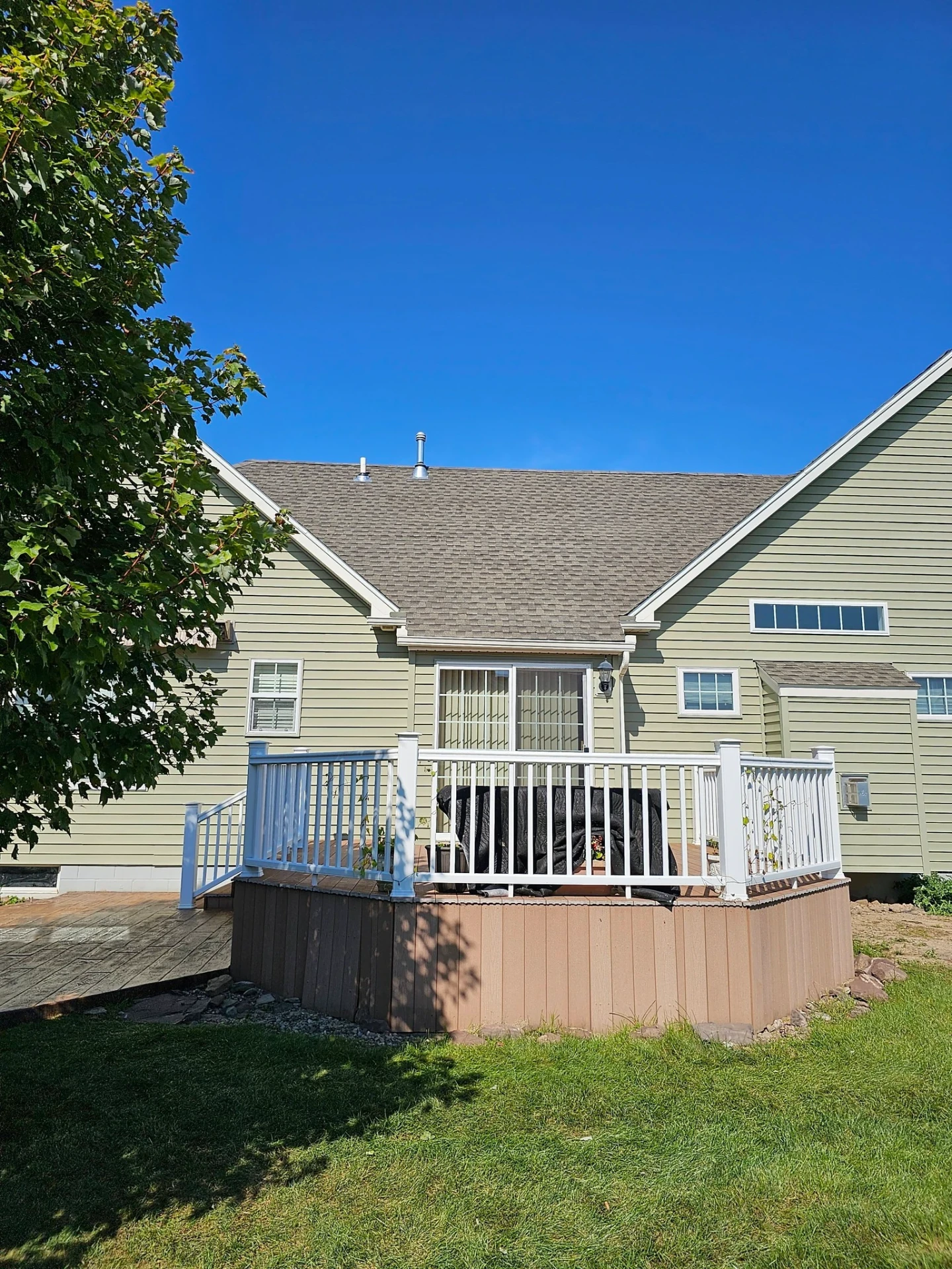 Existing raised back deck with white railings and wraparound accessibility ramp at a green sided home
