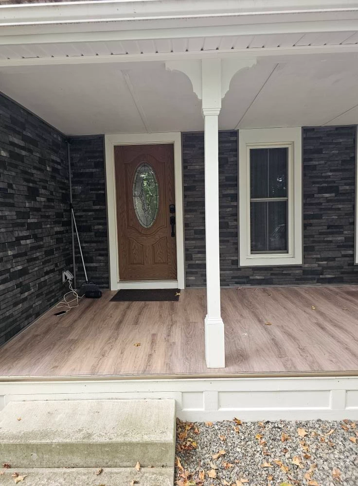 Front porch with charcoal stone veneer walls, oak entry door with oval glass and laminate flooring