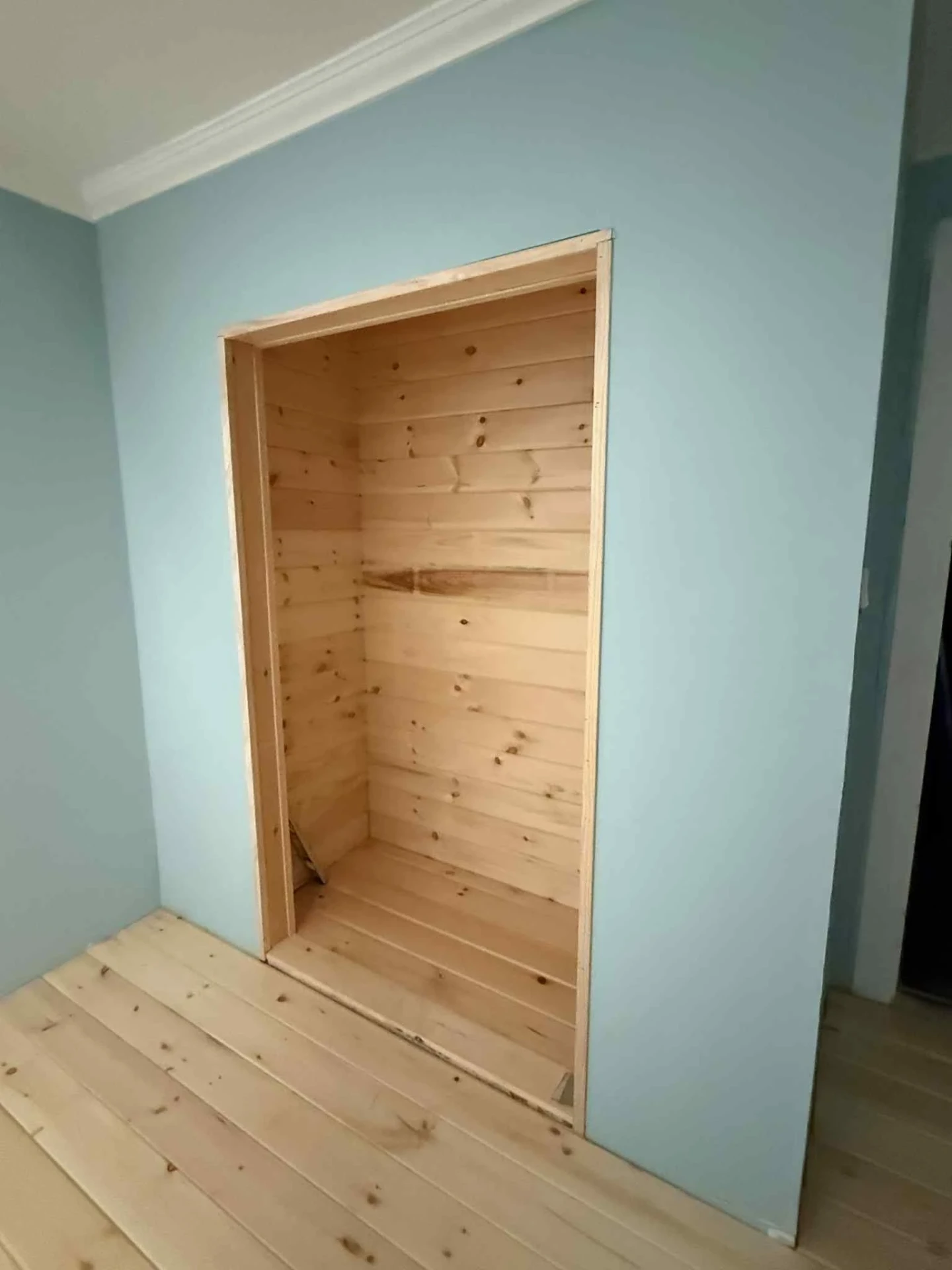 Built in pine closet alcove with shiplap interior in a freshly painted blue room