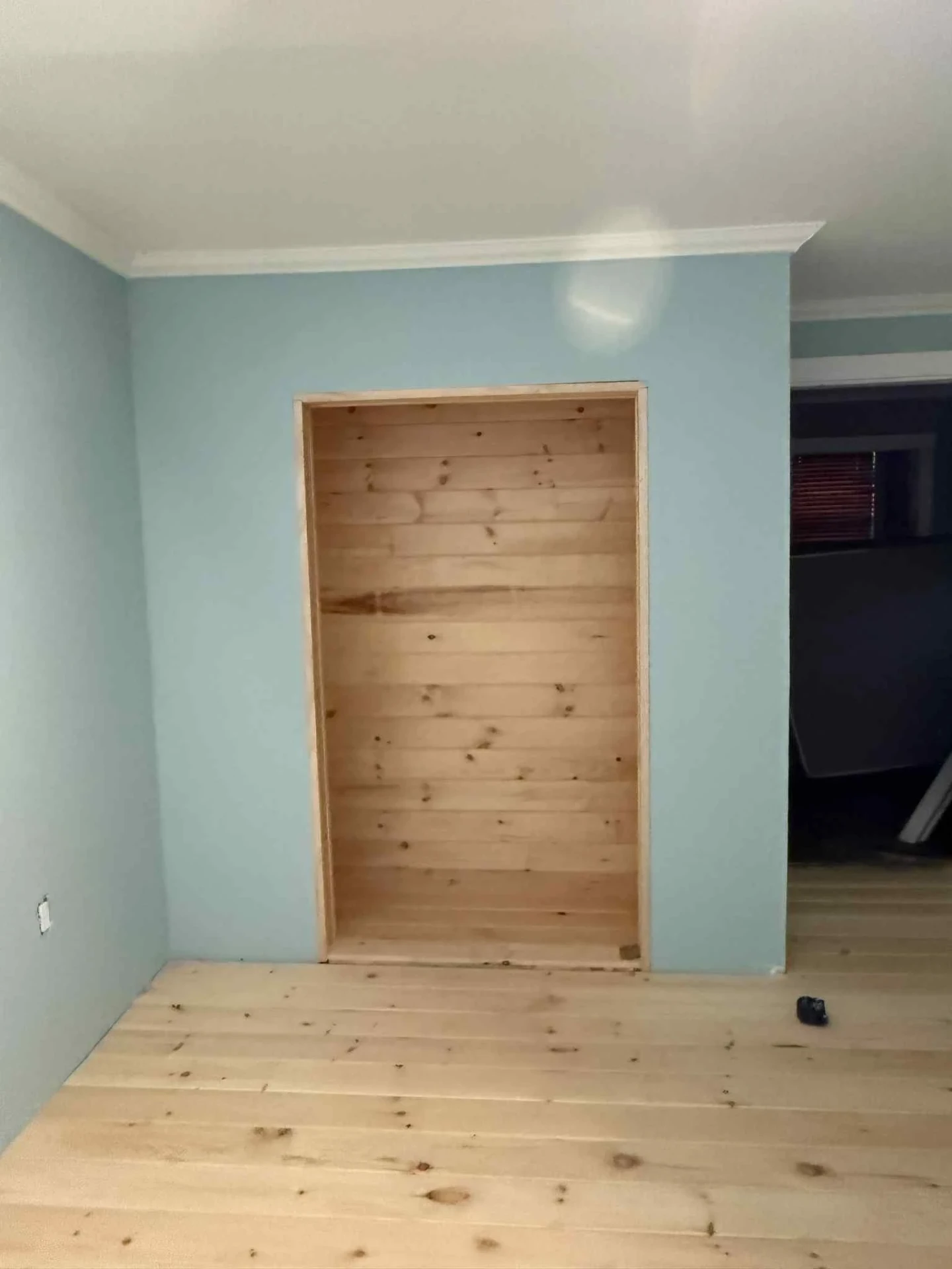 Interior built in pine nook framed into a soft blue wall with new pine plank flooring