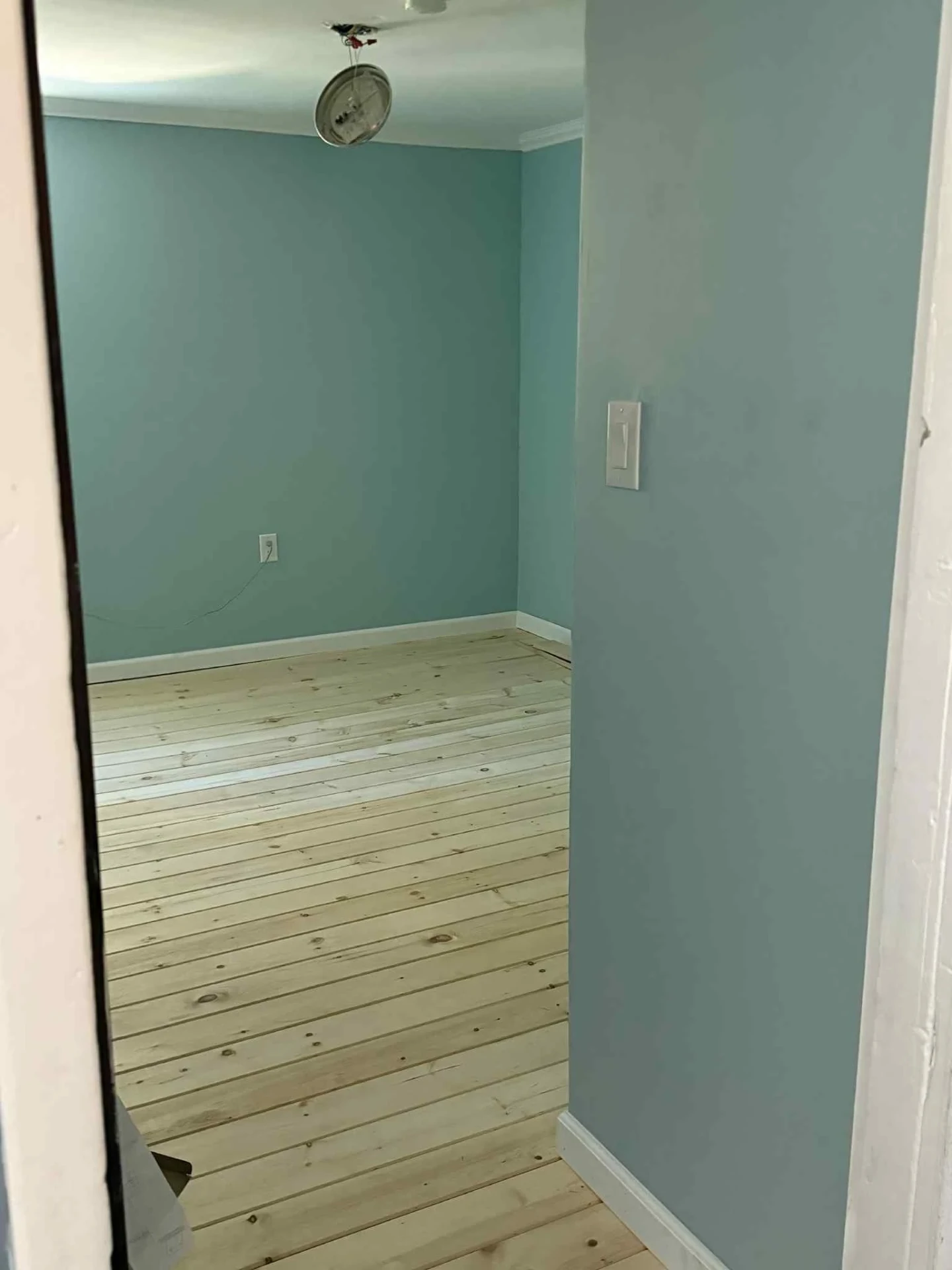 Empty bedroom with soft blue paint, white trim and fresh pine plank floors