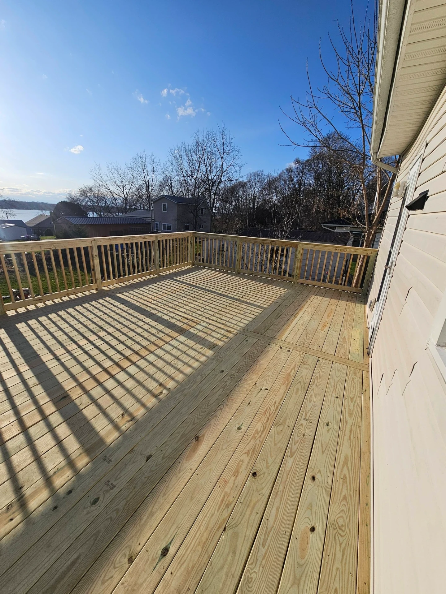Pressure treated lake view deck with full perimeter railings and long shadow lines from the spindles