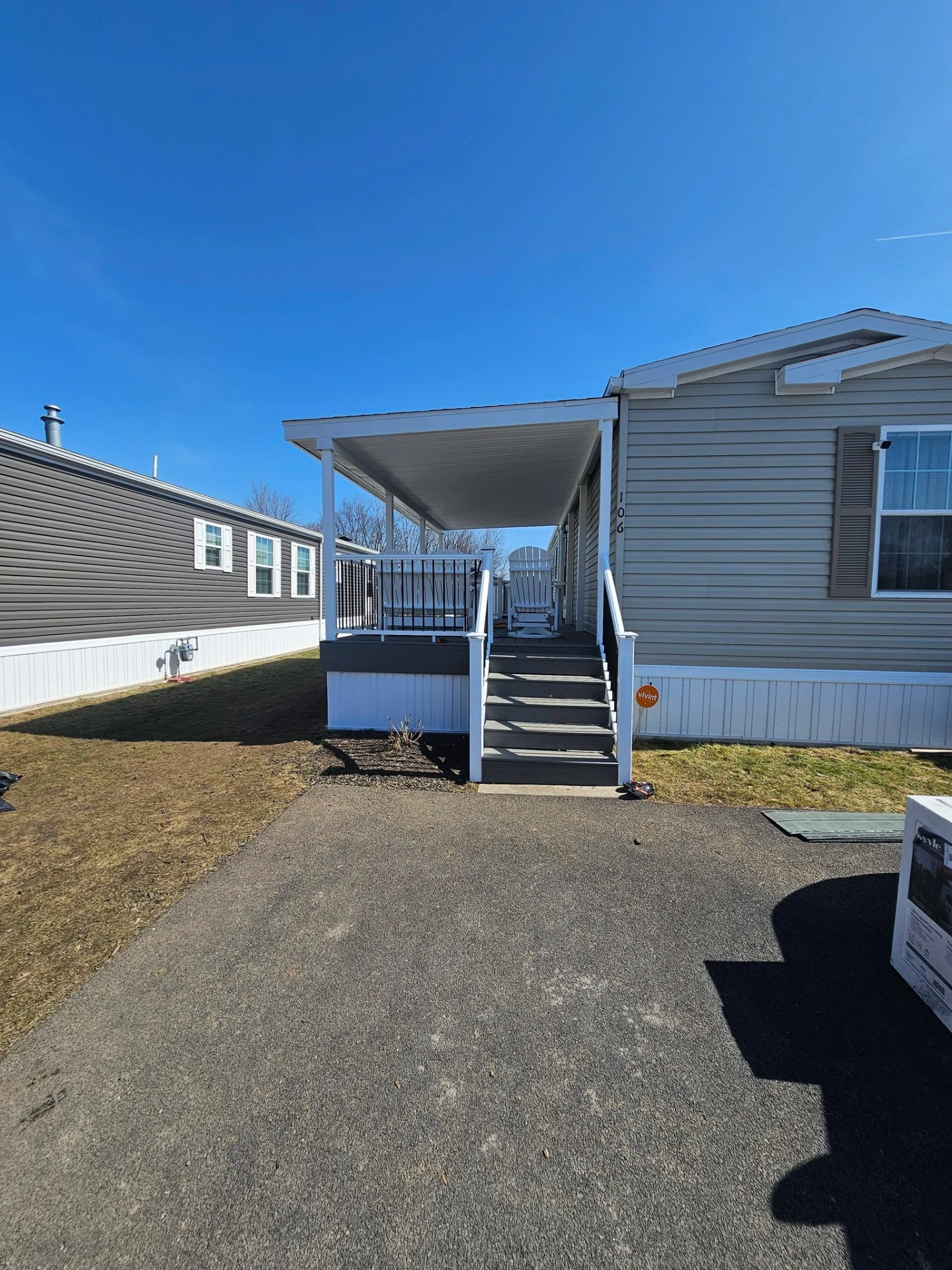 Manufactured home covered front porch with white posts, composite stairs and black aluminum railings