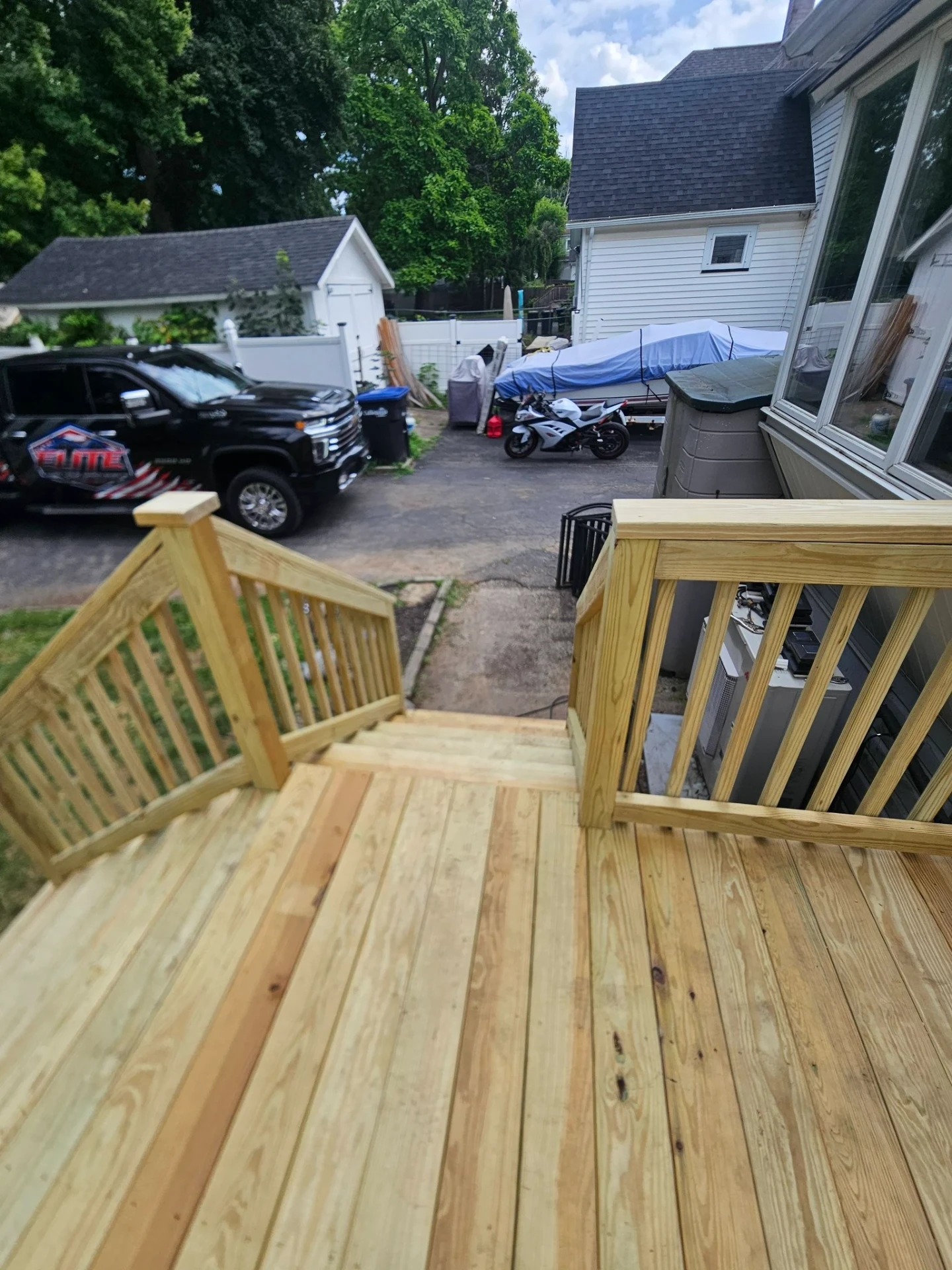 Top of a pressure treated deck staircase looking out toward the driveway and Eastside crew truck