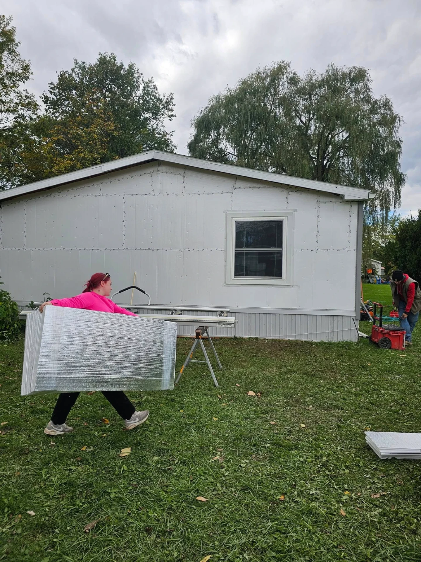 Eastside crew member carrying wrapped vinyl siding panels to a Finger Lakes job site
