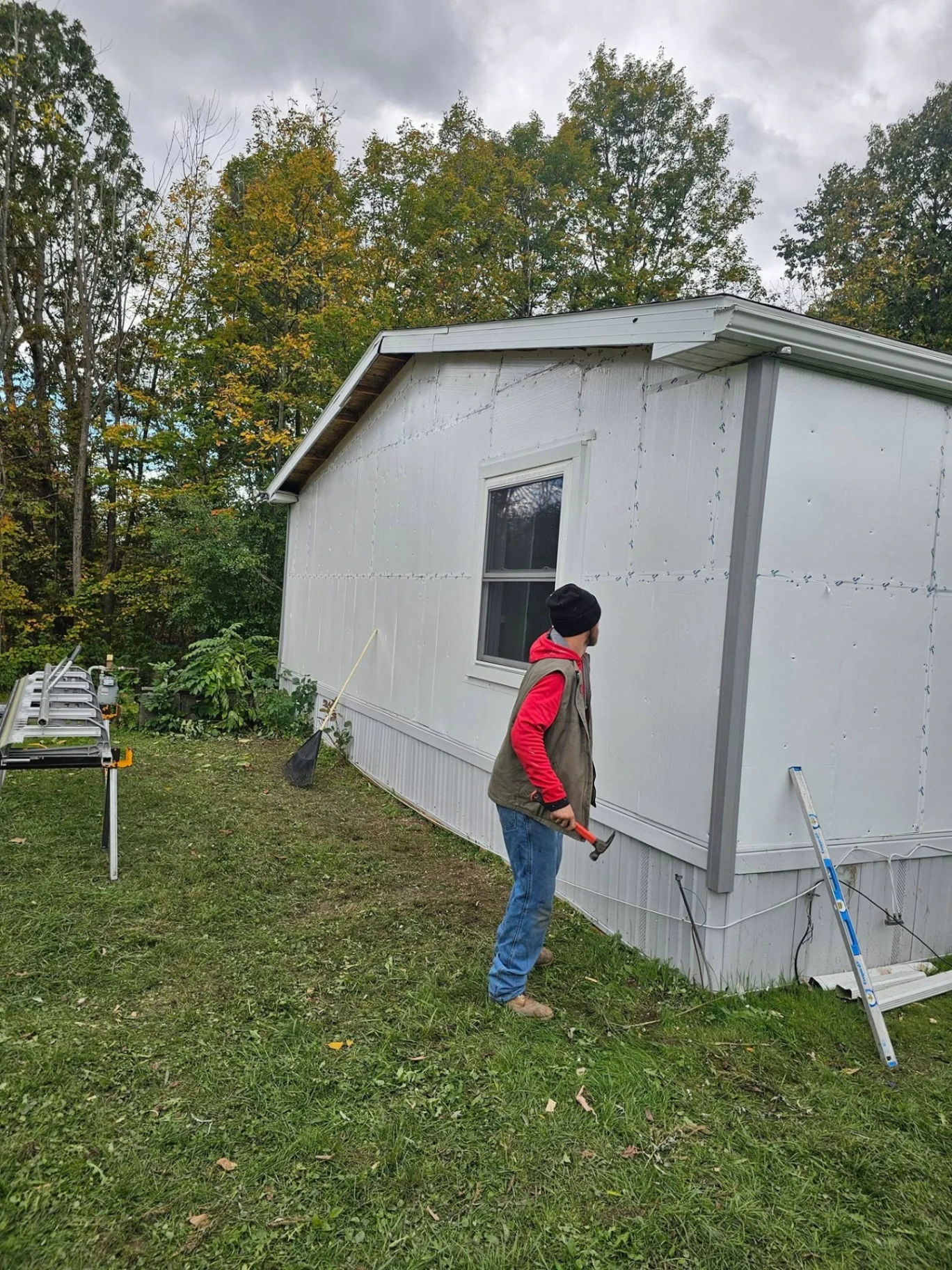 Crew member prepping a manufactured home wall with foam board before new siding install