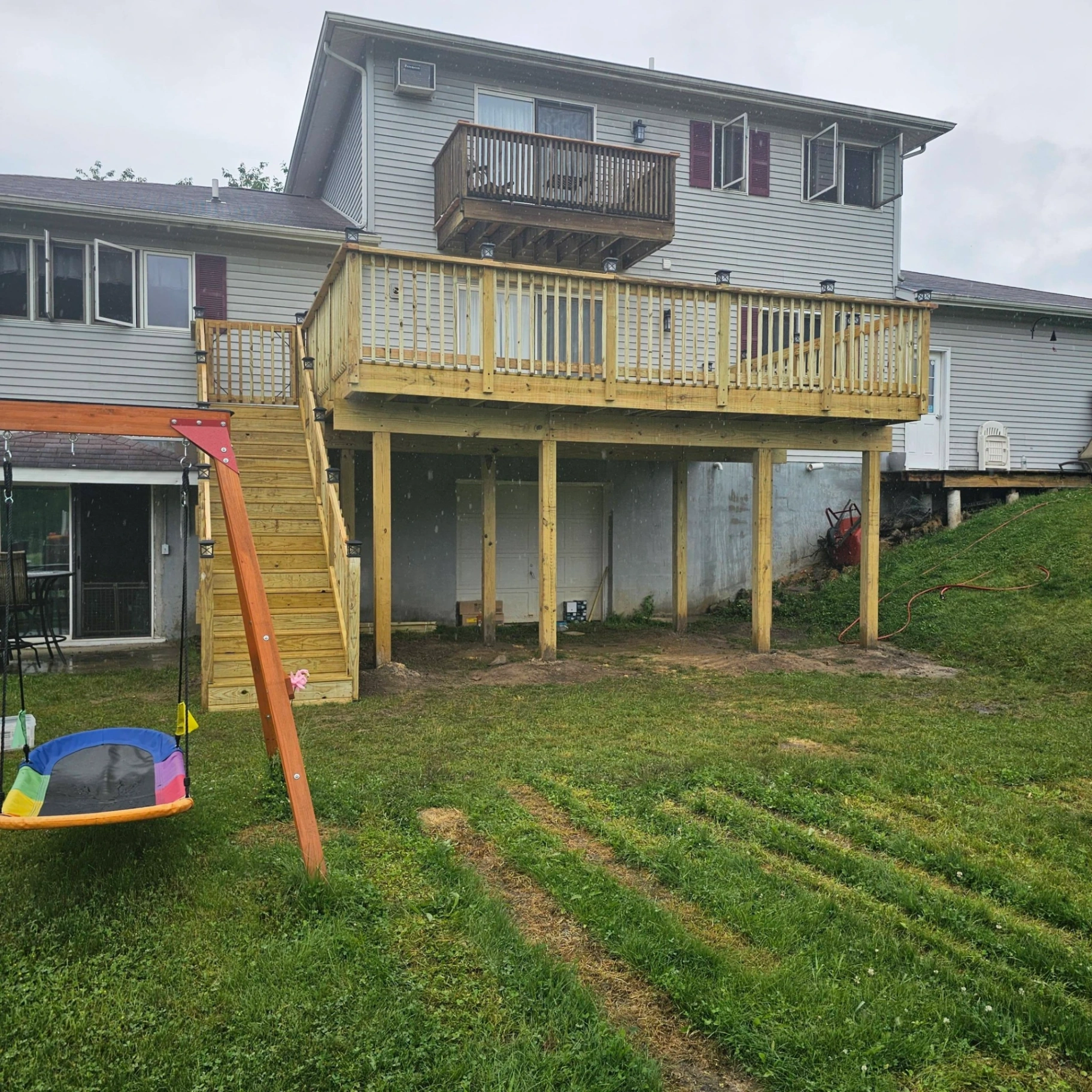 Elevated two story deck with full pressure treated railings and stairs built over a walkout garage