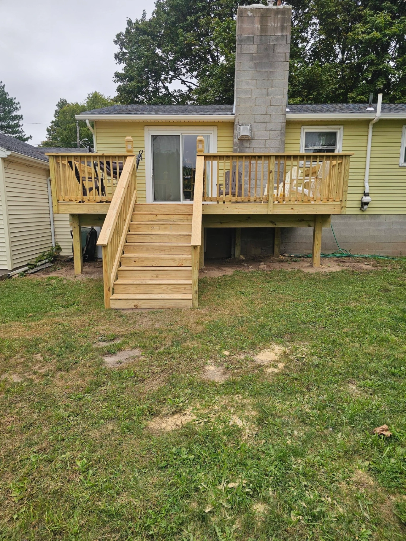 Finished pressure treated back deck with center stairs and full railings on a yellow ranch home